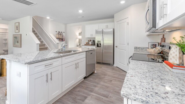 209 Wood St, La Grange, NC 28551 - kitchen featuring stainless steel appliances, a sink, a kitchen island with sink, white cabinetry, and light wood finished floors