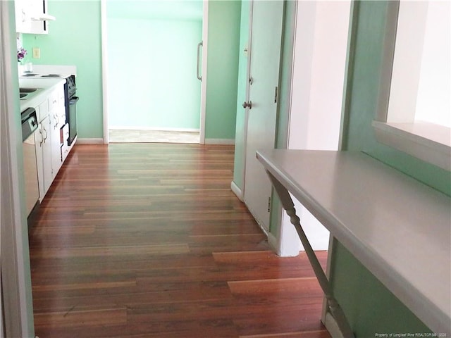 5609 Bowman Ct, Fayetteville, NC 28304 - kitchen featuring white cabinets, wood finished floors, under cabinet range hood, baseboards, and light countertops