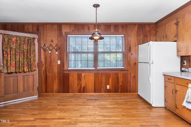 411 W Killiegrey St, Lillington, NC 27546 - kitchen featuring freestanding refrigerator, wooden walls, light wood-style flooring, ornamental molding, and brown cabinets