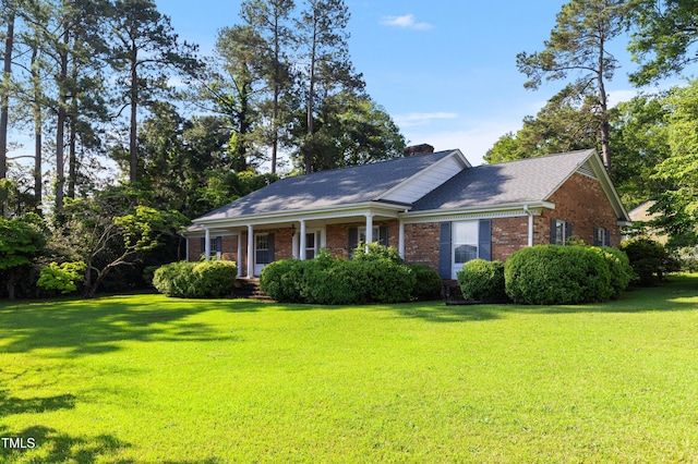 411 W Killiegrey St, Lillington, NC 27546 - view of front facade featuring brick siding, a front yard, a chimney, covered porch, and roof with shingles
