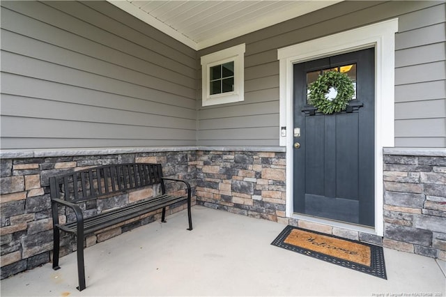 doorway to property with a porch and stone siding