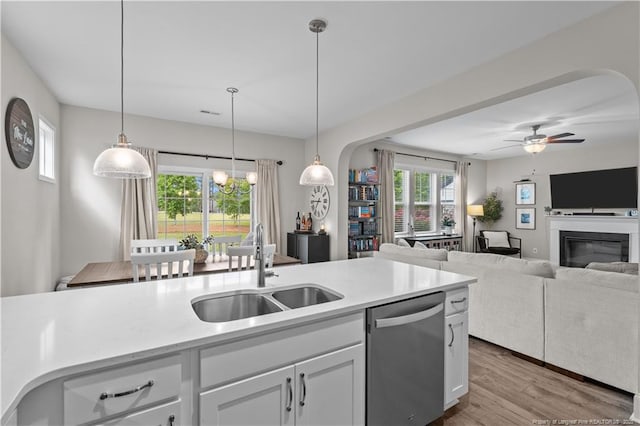 kitchen with dishwasher, a sink, light countertops, wood finished floors, and white cabinetry