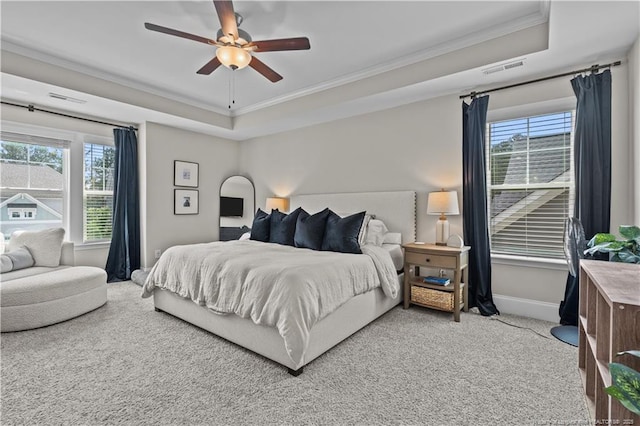bedroom featuring crown molding, a raised ceiling, multiple windows, carpet flooring, and baseboards