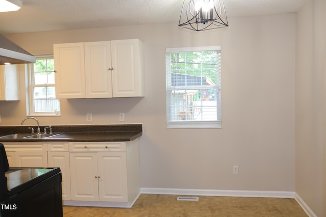 1536 Granville St, Burlington, NC 27215 - kitchen with a sink, dark countertops, white cabinetry, a chandelier, and baseboards