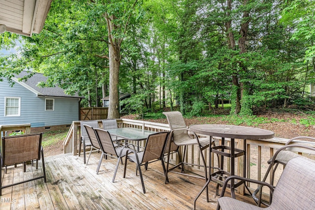 wooden deck featuring outdoor dining space and view of wooded area