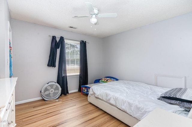 bedroom featuring light wood-type flooring, baseboards, a textured ceiling, and a ceiling fan