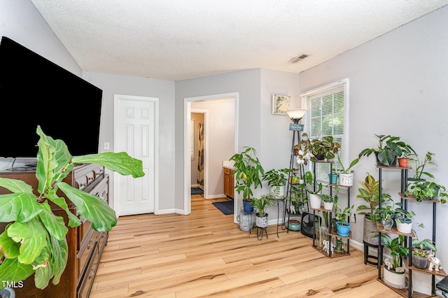 sitting room featuring wood finished floors, a textured ceiling, and baseboards