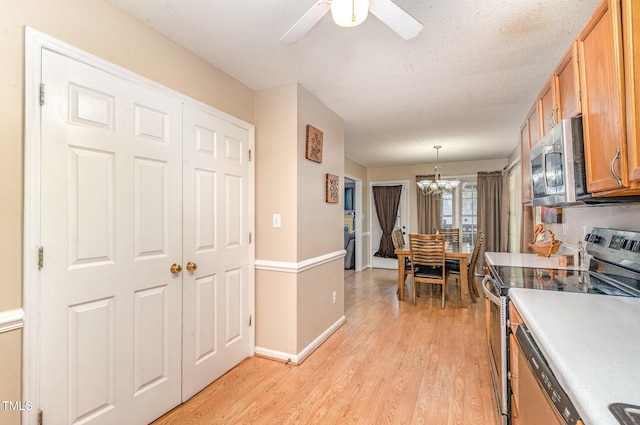 kitchen featuring stainless steel appliances, a chandelier, light wood-style flooring, ceiling fan, and light countertops