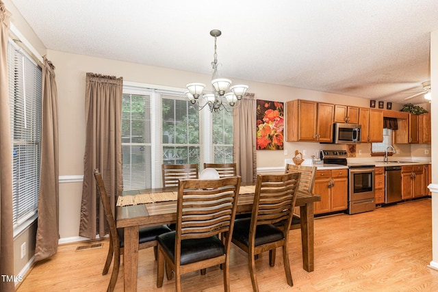 dining room featuring a chandelier, light wood-style floors, a textured ceiling, and baseboards