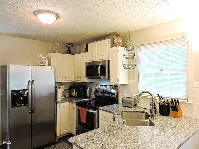 8 Woodsprite Ct, Durham, NC 27703 - kitchen with appliances with stainless steel finishes, a sink, a textured ceiling, a peninsula, and light stone counters