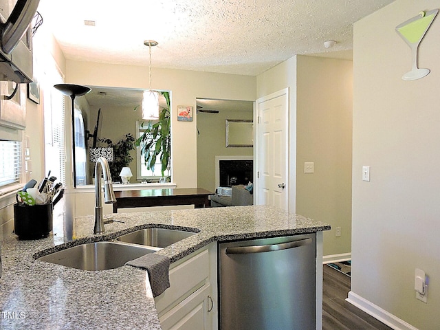 8 Woodsprite Ct, Durham, NC 27703 - kitchen with stainless steel dishwasher, a sink, dark stone counters, dark wood-type flooring, and hanging light fixtures