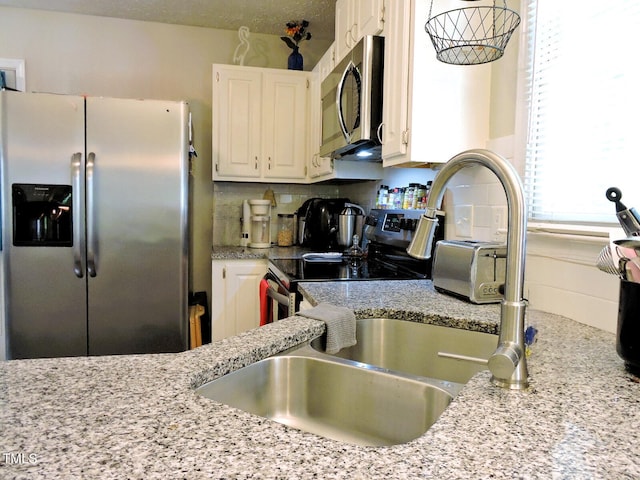 8 Woodsprite Ct, Durham, NC 27703 - kitchen featuring stainless steel appliances, white cabinets, backsplash, light stone countertops, and a sink