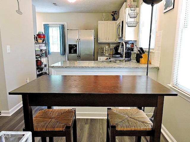 8 Woodsprite Ct, Durham, NC 27703 - kitchen featuring appliances with stainless steel finishes, white cabinets, dark wood-style flooring, baseboards, and a peninsula
