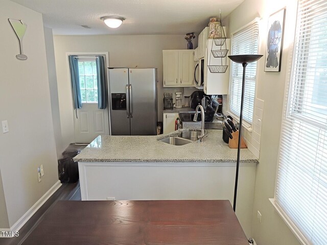 8 Woodsprite Ct, Durham, NC 27703 - kitchen featuring appliances with stainless steel finishes, a peninsula, a sink, white cabinetry, and baseboards