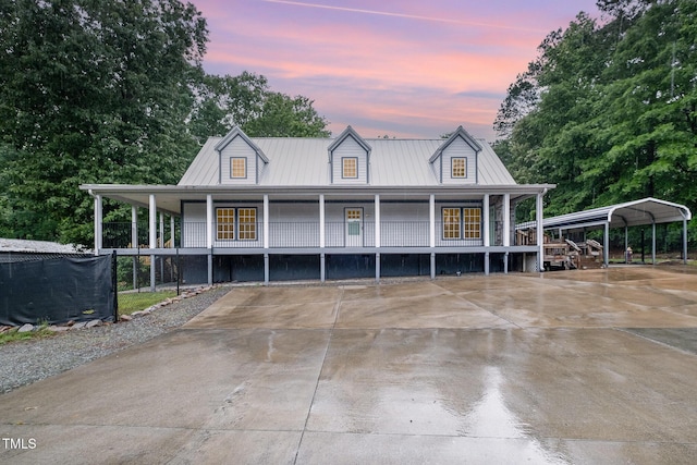 view of front of property featuring covered porch, a detached carport, driveway, and metal roof