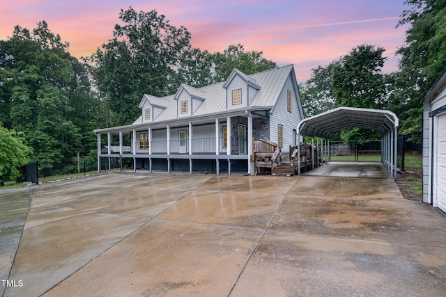view of front of house with a detached carport, a porch, concrete driveway, metal roof, and fence