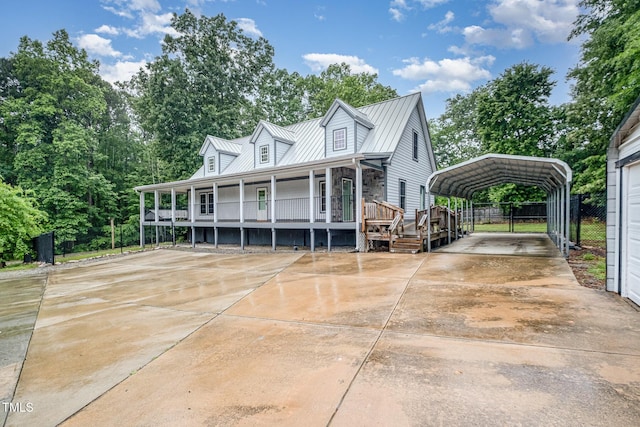 view of front facade with a detached carport, covered porch, driveway, fence, and metal roof
