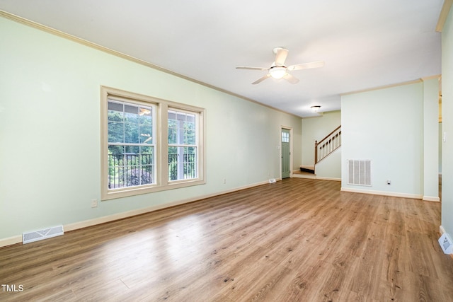unfurnished living room with crown molding, ceiling fan, wood finished floors, stairway, and baseboards