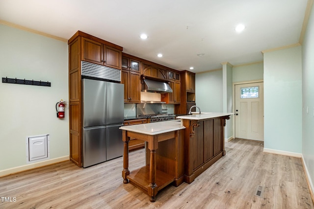 kitchen featuring built in refrigerator, ornamental molding, baseboards, light countertops, and under cabinet range hood