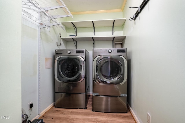 laundry area with wood finished floors, washing machine and clothes dryer, and baseboards