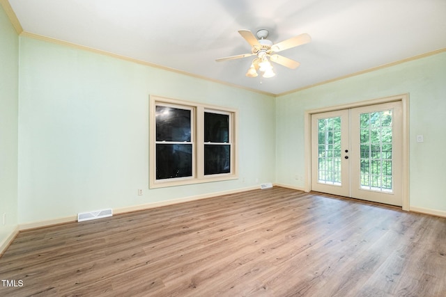 empty room featuring french doors, ornamental molding, wood finished floors, and baseboards