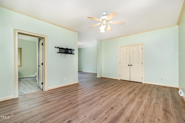 empty room with crown molding, ceiling fan, wood finished floors, and baseboards