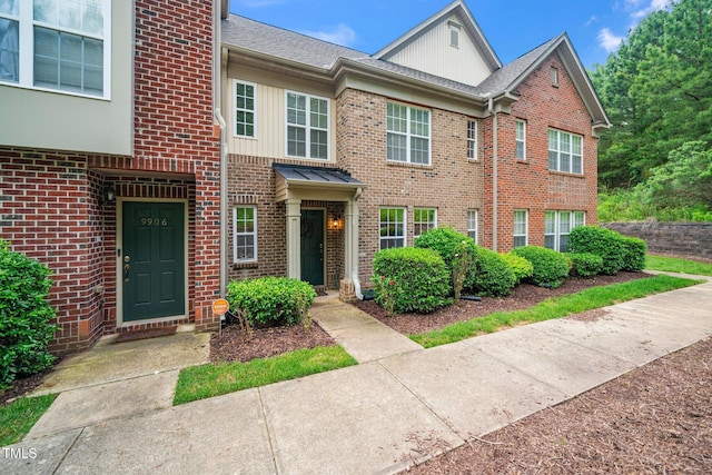 multi unit property with brick siding, a shingled roof, and board and batten siding
