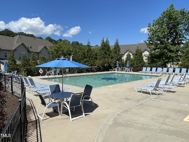 community pool with fence and a patio area