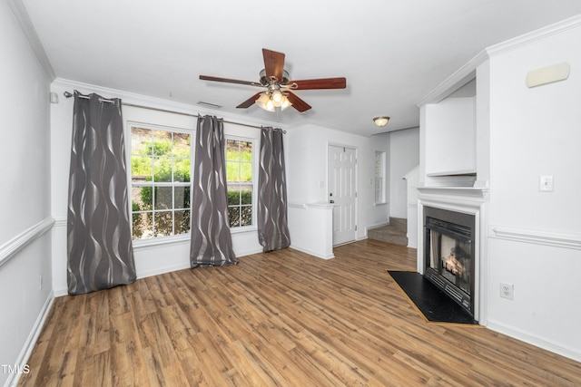 unfurnished living room with a ceiling fan, light wood-style floors, a fireplace with flush hearth, baseboards, and ornamental molding