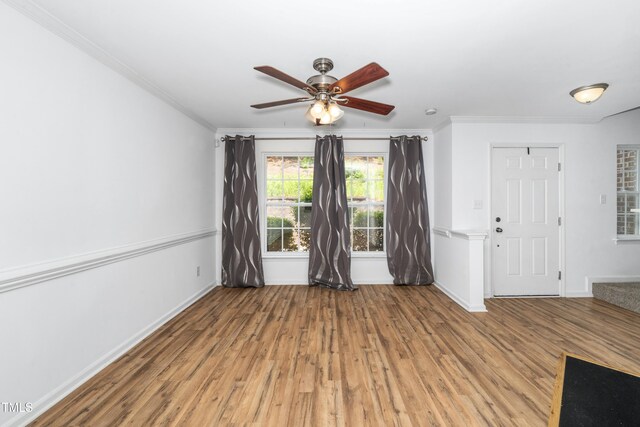 empty room with ceiling fan, ornamental molding, light wood-type flooring, and baseboards