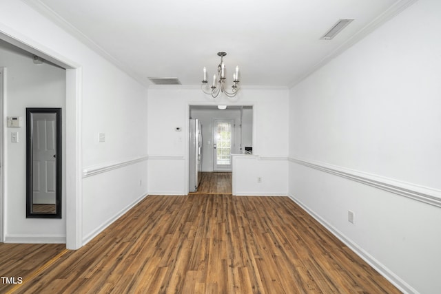 unfurnished dining area featuring a chandelier, wood finished floors, baseboards, and crown molding