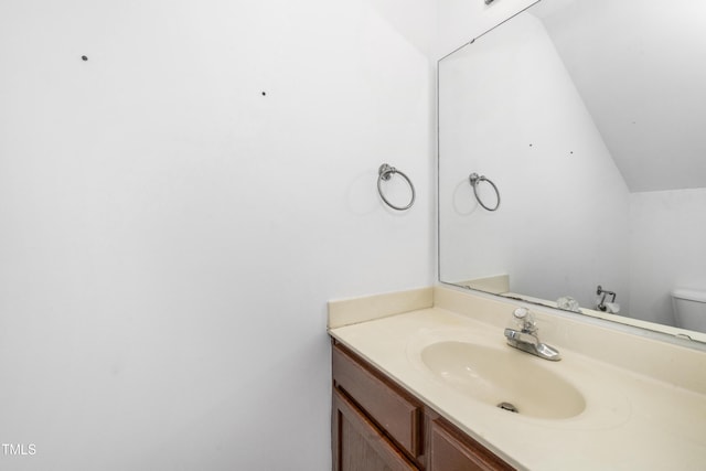 half bath with vanity, toilet, and lofted ceiling