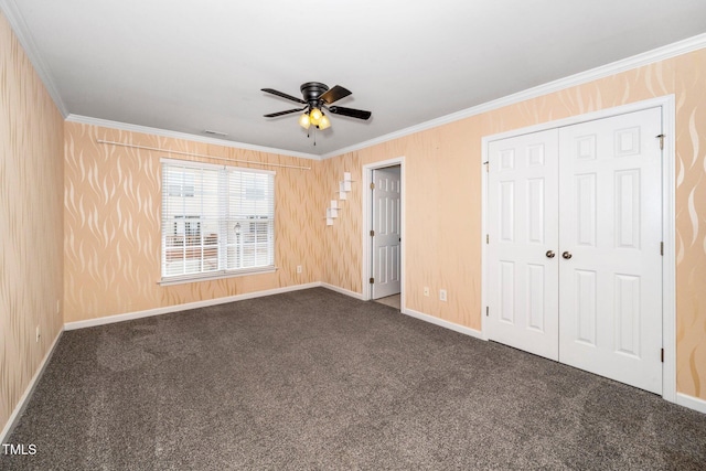 unfurnished bedroom featuring carpet floors, crown molding, baseboards, a closet, and a ceiling fan