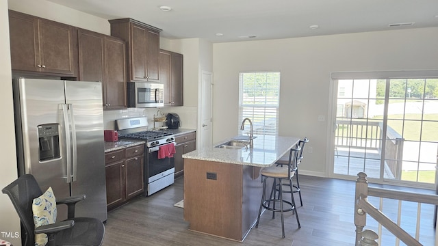 904 Romeria Dr, Durham, NC 27713 - kitchen featuring appliances with stainless steel finishes, dark wood-style flooring, an island with sink, and light stone countertops