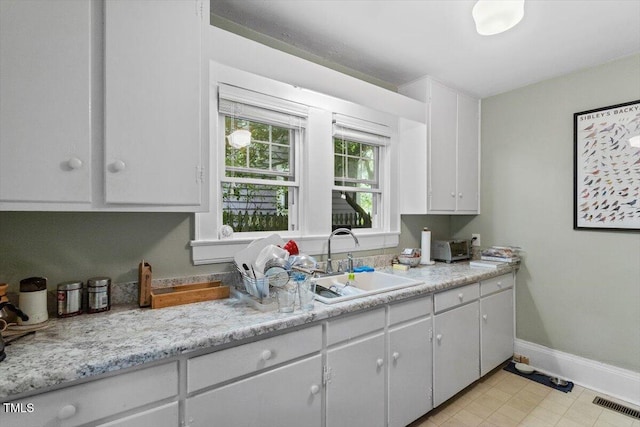 1314 Glendale Ave, Durham, NC 27701 - kitchen featuring a sink, light countertops, baseboards, and white cabinets