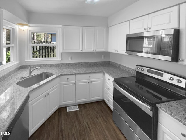 kitchen with stainless steel appliances, a sink, dark wood finished floors, white cabinets, and light stone countertops