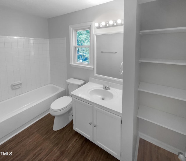 bathroom featuring wood finished floors, toilet, vanity, and a tub