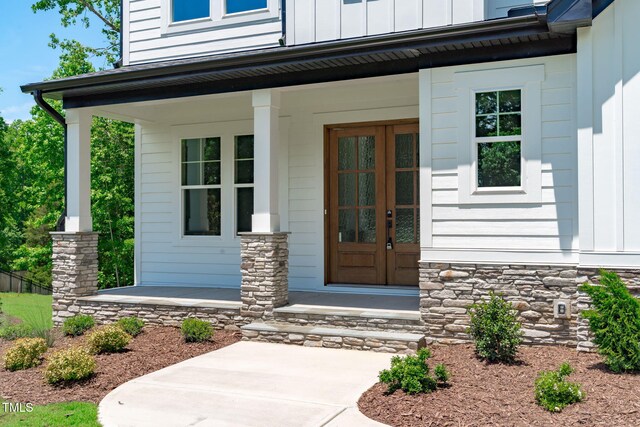248 Ashford Dr, Pittsboro, NC 27312 - entrance to property with covered porch, board and batten siding, stone siding, and french doors