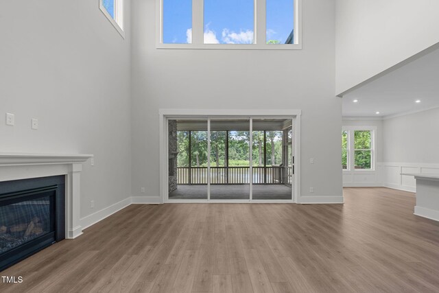 248 Ashford Dr, Pittsboro, NC 27312 - unfurnished living room featuring a towering ceiling, a glass covered fireplace, wood finished floors, and recessed lighting