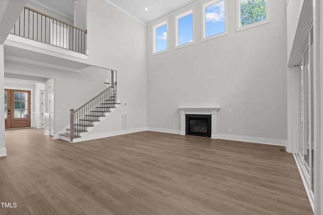 248 Ashford Dr, Pittsboro, NC 27312 - unfurnished living room with a high ceiling, baseboards, stairway, wood finished floors, and crown molding