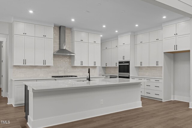 248 Ashford Dr, Pittsboro, NC 27312 - kitchen featuring wall chimney exhaust hood, a sink, white cabinets, a spacious island, and double wall oven
