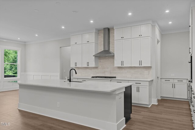 248 Ashford Dr, Pittsboro, NC 27312 - kitchen with wall chimney range hood, a sink, white cabinetry, wood finished floors, and ornamental molding