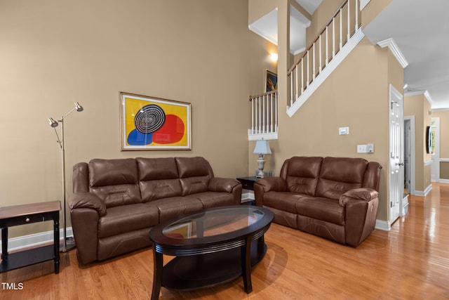 living area featuring light wood-style flooring, baseboards, and ornamental molding