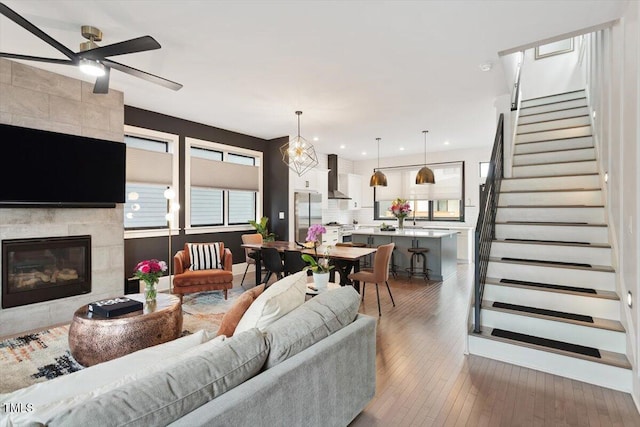 living room featuring stairway, ceiling fan, wood-type flooring, a tile fireplace, and recessed lighting