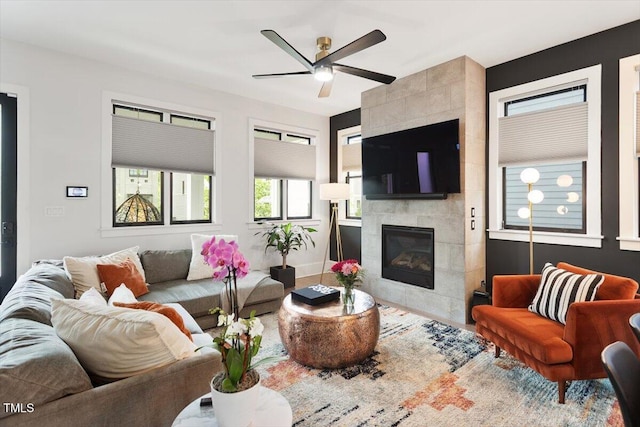 living room featuring a ceiling fan and a tiled fireplace