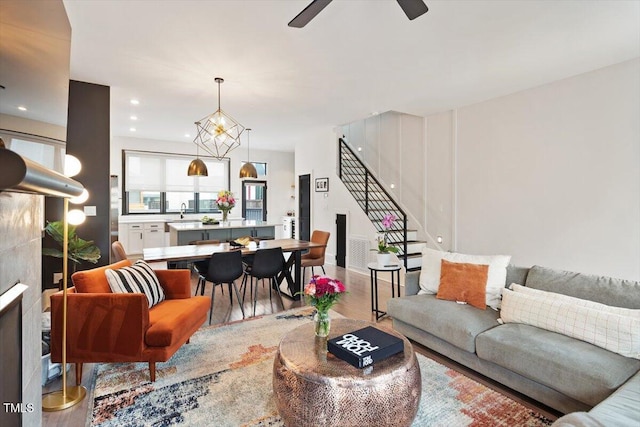 living area featuring stairs, wood finished floors, ceiling fan, and recessed lighting
