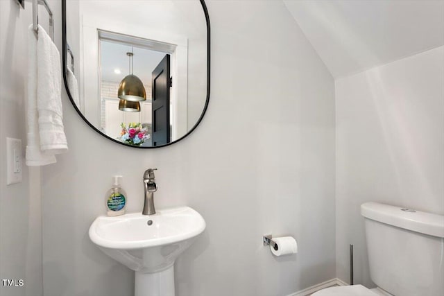 bathroom featuring toilet, a sink, and vaulted ceiling
