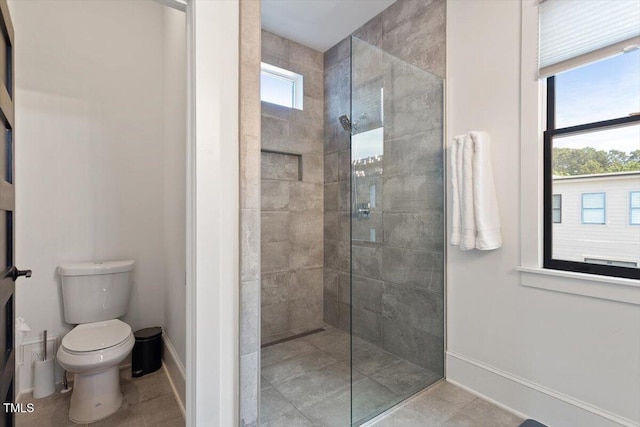bathroom featuring walk in shower, baseboards, and toilet
