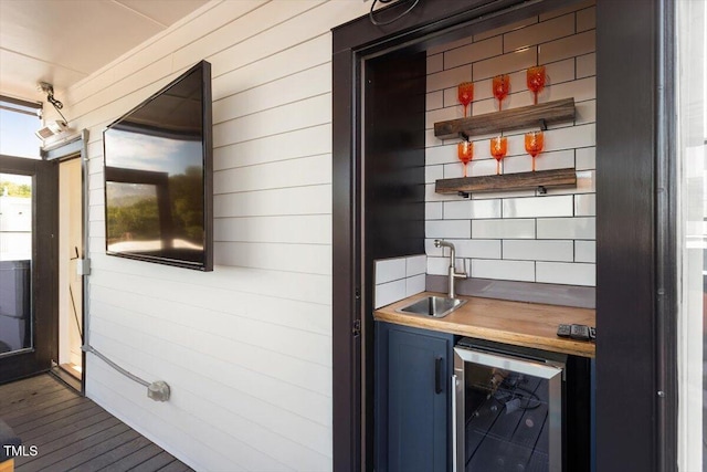 indoor wet bar with beverage cooler, wood walls, and wood finished floors