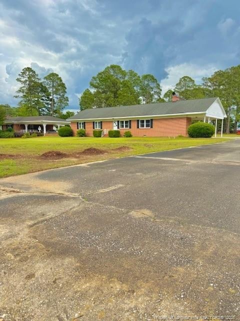 209 S Main St, Salemburg, NC 28385 - ranch-style house with a front yard, driveway, and a chimney